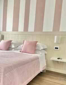 um quarto com uma cama rosa com almofadas cor-de-rosa e brancas em Le Camere di Libero e Roberta em Tropea