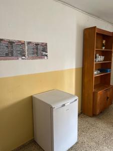 a small white refrigerator in a room with a shelf at Albergue municipal in San Martín del Camino