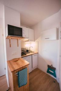 una pequeña cocina con armarios blancos y fregadero en Mon studio cosy à Pessac - Bordeaux, en Pessac