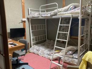 een slaapzaal met 2 stapelbedden en een bureau bij Guest House Salt Beach in Yokkaichi