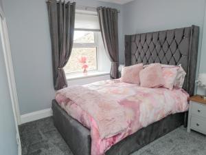 a bedroom with a bed with pink sheets and a window at 4 Tyne View in Hexham