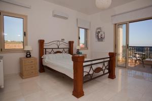 a bedroom with a bed and a table and windows at Eagles Cliff Villa in Kathikas