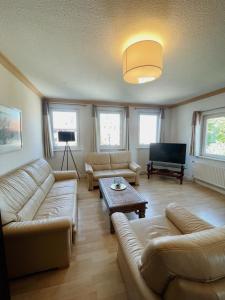 uma sala de estar com sofás, uma mesa e uma televisão em Apartment Josephine em Lübeck