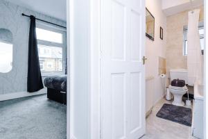 a white bathroom with a toilet and a window at 65 inch TV in Modern 2 Bed Hideaway in Bradford