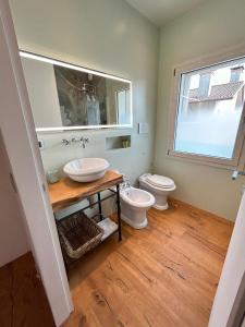 a bathroom with a toilet and a sink and a window at L'incanto Home 1 in Cittadella