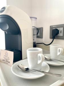 two cups and spoons on a counter with a toaster at Le Camere di Libero e Roberta in Tropea