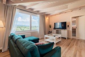 Melena Premium Suites في رودا: غرفة معيشة بها أريكة خضراء وتلفزيون