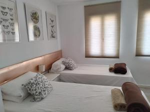 2 letti in una camera con pareti e finestre bianche di Moon Valencia a Valencia