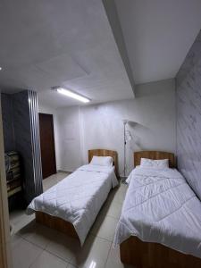 2 bedden in een kleine kamer met witte lakens bij Nice tow bedrooms by snake pool in talapay in Aqaba