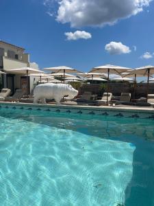 a pool with a statue of a rhino next to umbrellas at Les Loges du Luberon in Coustellet