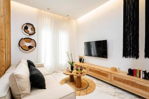 a living room with a white couch and a tv at Naxos Petite In Town in Naxos Chora