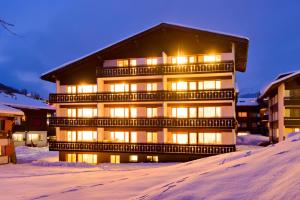 a large building with lights on in the snow at Haus Alfa in Saas-Fee