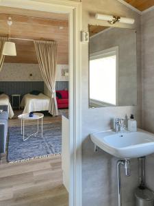 a bathroom with a sink and a bedroom at Strandbergs Stugor in Mariehamn