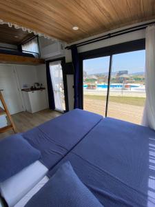 a bedroom with a blue bed and a large window at Lavira Tiny House Village in Bogazici