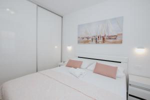 a white bedroom with a white bed with pink pillows at Royal Blue House 2 in Kaštela