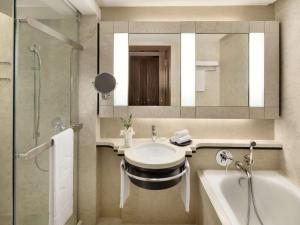 Shangri-La Kuala Lumpur في كوالالمبور: حمام مع حوض وحوض ومرآة