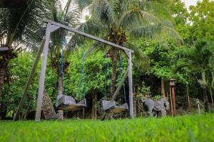an old swing set in a yard with palm trees at Hotel & Villa Bukit Indah Saumlaki by LeGreen 
