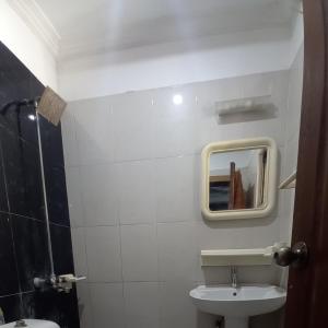 een witte badkamer met een wastafel en een spiegel bij Peaceful Low cost 2BR in Islamabad