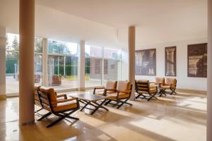 a group of chairs and tables in a room with windows at UNAHOTELS Bologna San Lazzaro in San Lazzaro di Savena