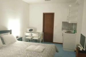 a bedroom with a bed and a table and a kitchen at My Colombo Place in Lisbon