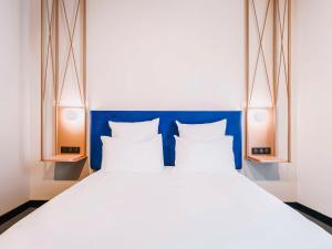 1 cama con cabecero azul y 2 lámparas en Mercure Brest Centre Port en Brest