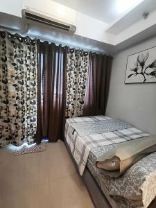 a bedroom with a bed and a window with curtains at Reese @ Sea Residences Manila in Manila