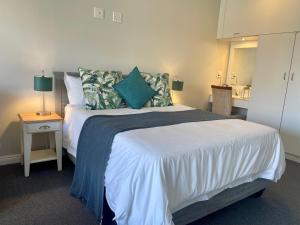 1 dormitorio con 1 cama grande con almohadas azules en Port Edge - Ships Bell, Port St Francis Bay, en St Francis Bay