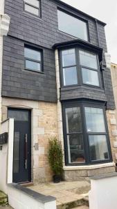 a brick house with a black door and windows at Hyper-central Newquay, sleeps 3 in Newquay