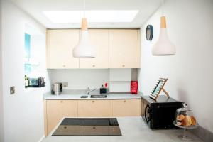 a kitchen with white cabinets and a black refrigerator at Hyper-central Newquay, sleeps 3 in Newquay