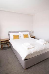 a bed with white sheets and yellow pillows on it at Hyper-central Newquay, sleeps 3 in Newquay