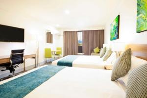 una camera d'albergo con 2 letti e una scrivania di Metro Aspire Hotel Sydney a Sydney