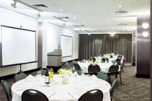 una sala de conferencias con mesas y sillas y una pantalla de proyección en Metro Aspire Hotel Sydney en Sídney