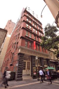 un alto edificio di mattoni rossi con gente che cammina davanti di Metro Apartments On Bank Place a Melbourne