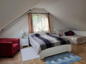 a bedroom with a bed and a red chair at Duzzogó Vendégház Agárd in Gárdony