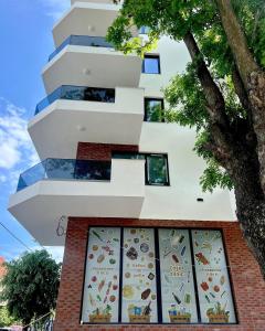 ein weißes Gebäude mit einem Baum davor in der Unterkunft Crystal Sands Residence in Eforie Nord