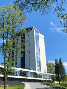 a tall white building with glass windows at Pieniny Grand Szczawnica in Szczawnica