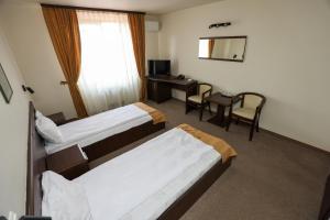 a hotel room with two beds and a desk at Hotel Dusan si Fiul Resita Sud in Reşiţa