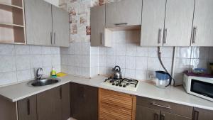 cocina con armarios blancos, fregadero y microondas en Дачна 37,CityRooms en Bila Tserkva