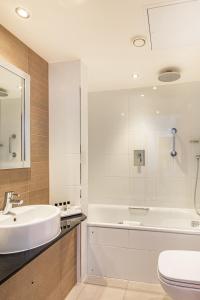 La salle de bains est pourvue d'un lavabo, d'une baignoire et de toilettes. dans l'établissement Thistle London Marble Arch, à Londres