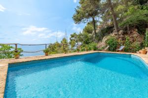 a swimming pool with two chairs in front of a mountain at Alconasser in Sóller