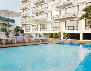 a woman sitting next to a hotel swimming pool at CH Hotel in Chiang Mai