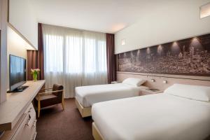 サン・ラッザロ・ディ・サーヴェナにあるUNAHOTELS Bologna San Lazzaroのベッド2台とテレビが備わるホテルルームです。