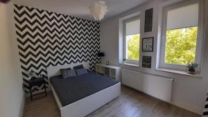um quarto com uma cama e duas janelas em Apartament Łubinowa em Toruń