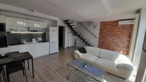 uma sala de estar com um sofá branco e uma parede de tijolos em Apartament Łubinowa em Toruń