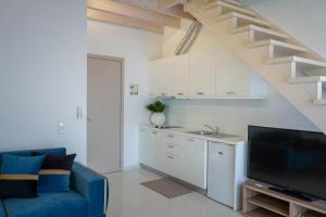 a living room with a blue couch and a kitchen at Liberte Maisonettes in Parga