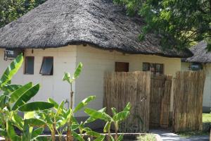 a small house with a thatched roof and a fence at Mpora River Lodge in Rundu