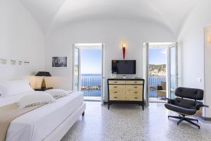 una camera con letto, TV e sedia di Roccobarocco Boutique Hotel a Ischia