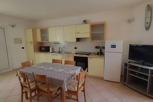 a kitchen with a table and chairs and a kitchen with a refrigerator at La veranda del Melograno - Pisticci in Pisticci