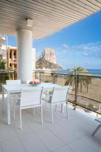 una mesa de comedor blanca y sillas en un balcón con vistas al océano en Apartamentos Vista Bella, en Calpe