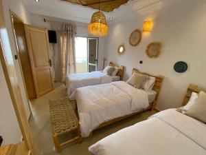 a bedroom with three beds and a chandelier at West coast surf house in Imsouane
